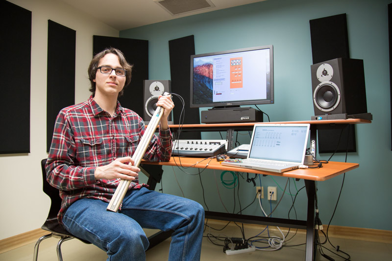 student sitting in front of computer with mixing board and speakers