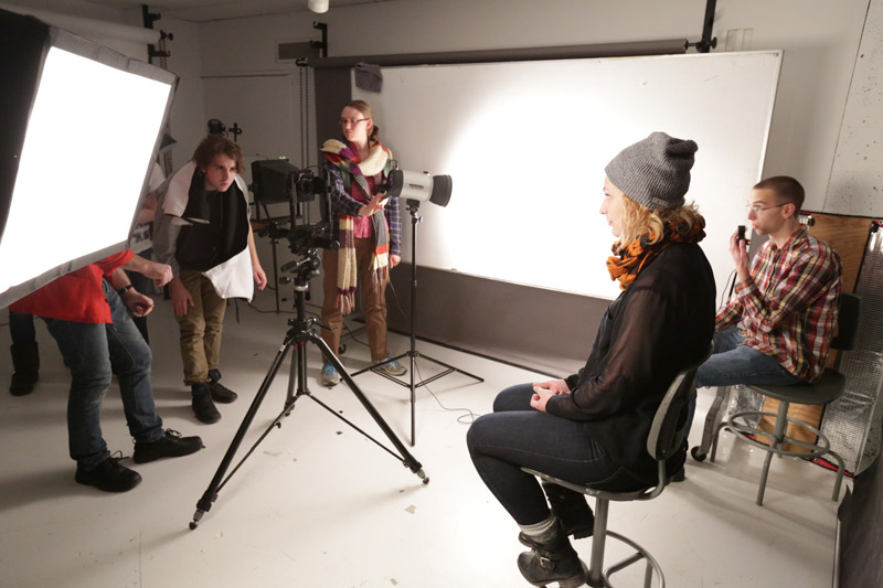 Student sitting on stool for photoshoot