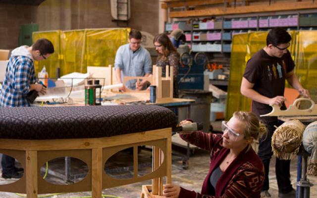 student upholstering bench in prop shop