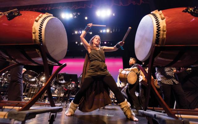 Taelynn playing taiko drums wearing cape and tunic