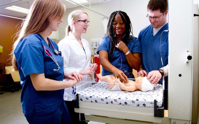 Students working with an infant mannequin