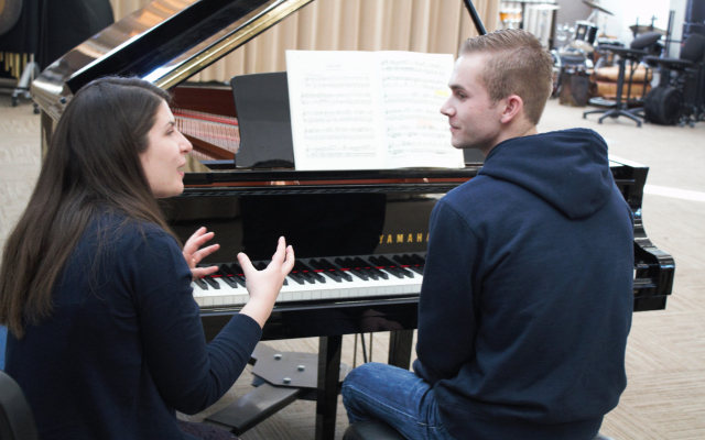 woman teaching piano to young man