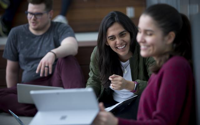 Two female students smiling while looking at tablet