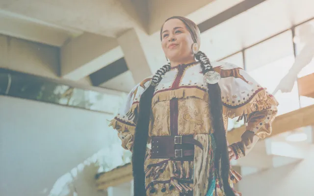 Indigenous woman wearing a jingle dress performs a traditional dance 