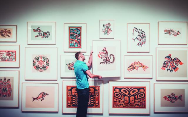 Person hanging artwork in the Hess Gallery