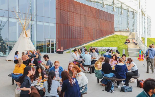 Students gathered around tables in an outdoor setting