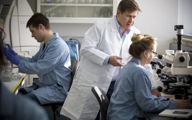 Students in a lab receiving direction from a professor