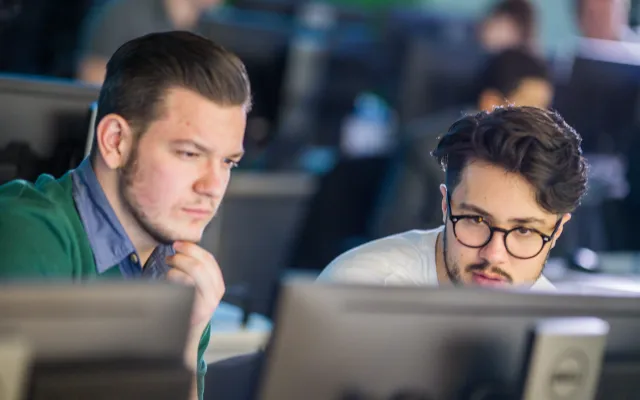 Two students intently focused on a computer screen