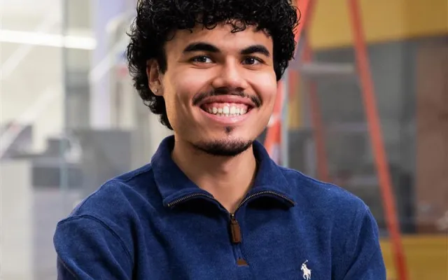 Photo of Alejandro in front of glass windows with the NMR machines in the background