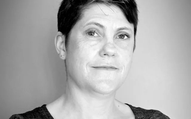 A black and white photograph of Mary-Ann McTrowe from the shoulders up.  She has short, dark hair, white skin, and is smiling.