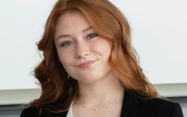 A photo of Rylee with a black blazer and white shirt in front of a white background.
