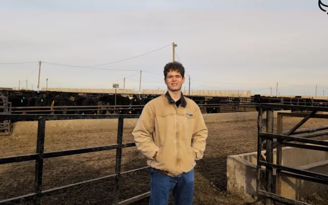 Young man standing in front of a cattle ranch