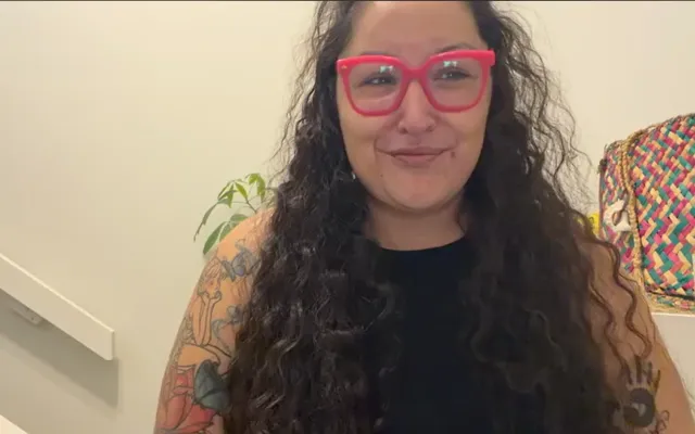 Woman with pink glasses in front of a home wall