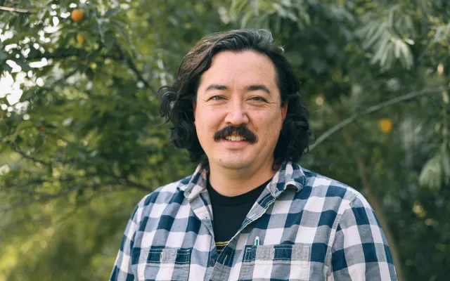 A man stands in front of a Russian olive tree