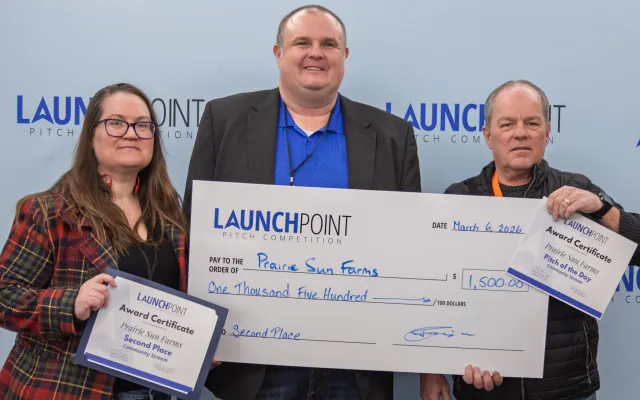 Two men holding a large cheque and a certificate in front of a blue backdrop.