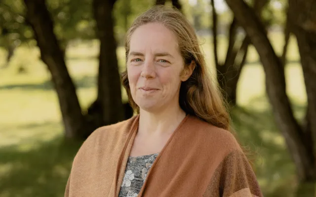 A woman standing in front of tree trunks