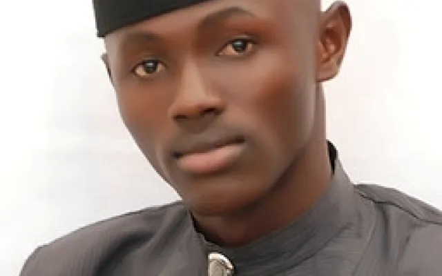 Akeem wearing a kufi hat and a black shirt.