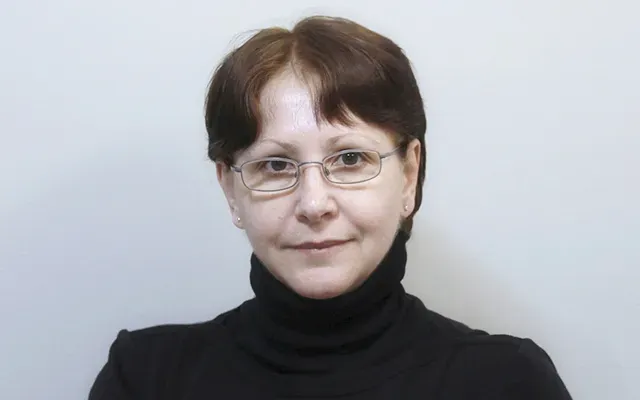Daniela wearing glasses and a black turtle neck sweater.