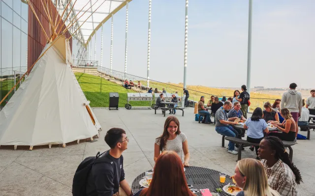 Students by teepee eating lunch together