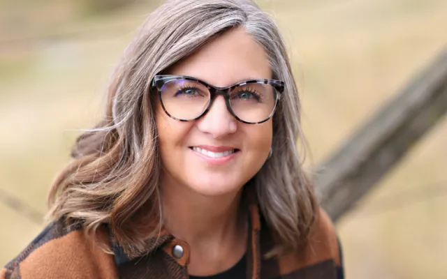 Tracy wearing glasses and a brown plaid jacket.
