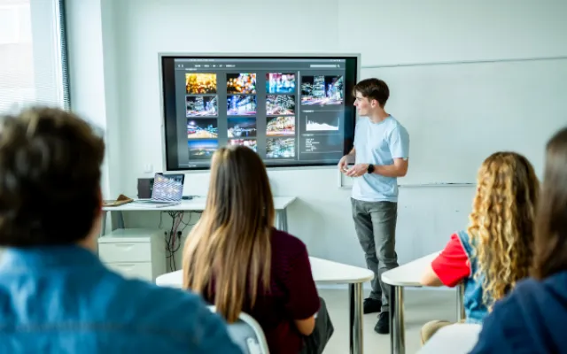 man at a computer screen at the front of a classroom