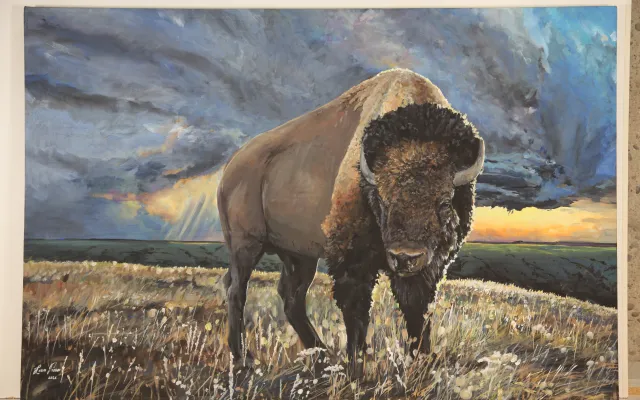 An acrylic painting of a buffalo standing in the coulees with storm clouds in the sky.