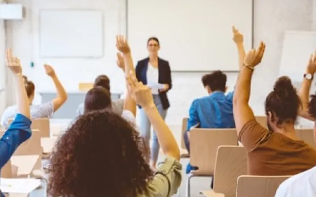 students in a classroom with hands raised