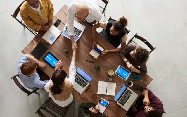 above view of 8 people seated at a table with computers