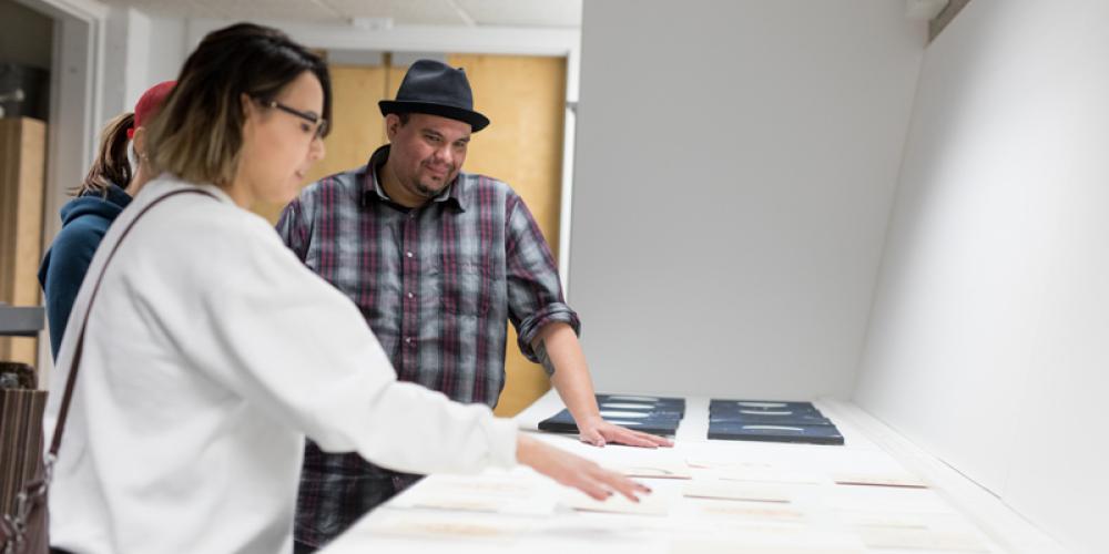 students looking at printed art on a table