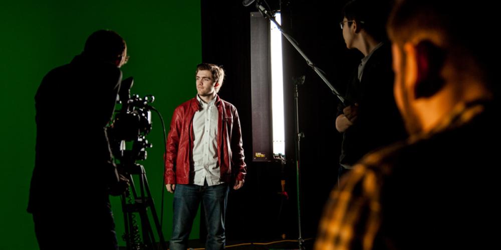 behind the scenes shot of student lit in front of green screen