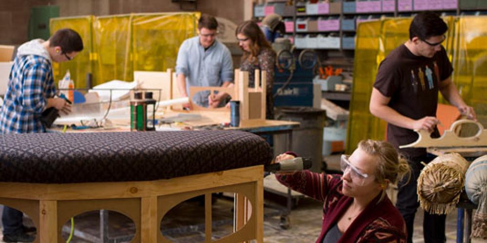 student upholstering bench in prop shop