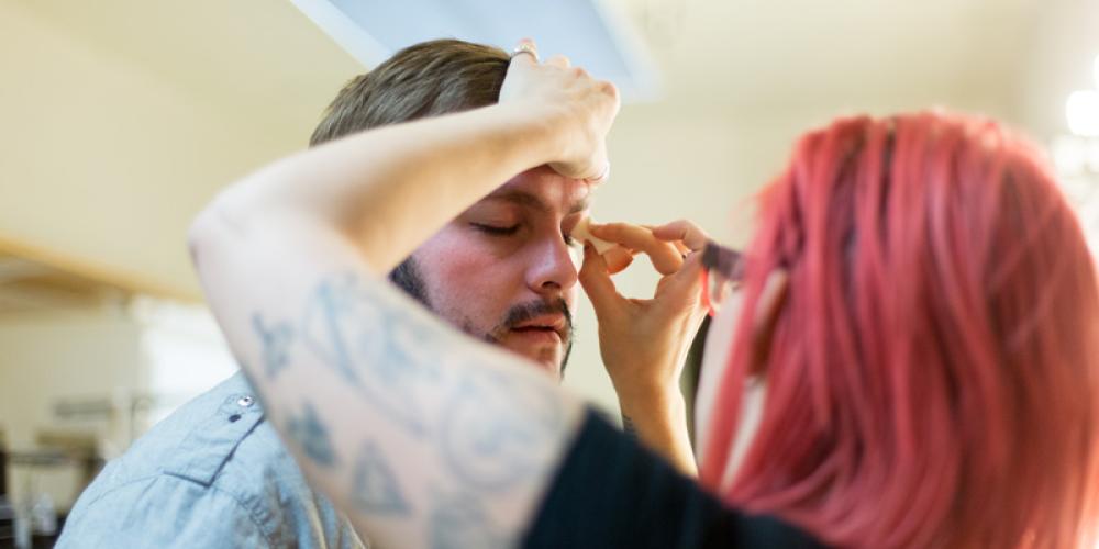 Student applying makeup to actor