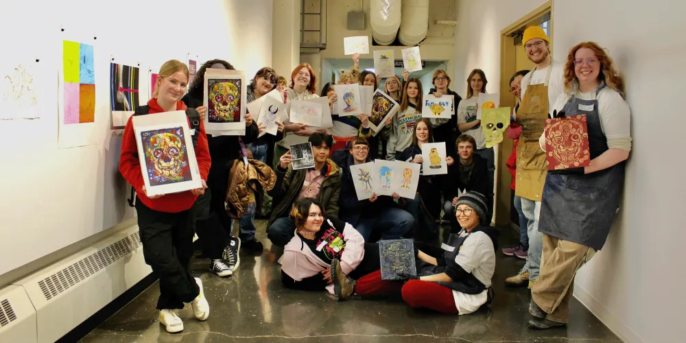 students holding up prints they made in a workshop