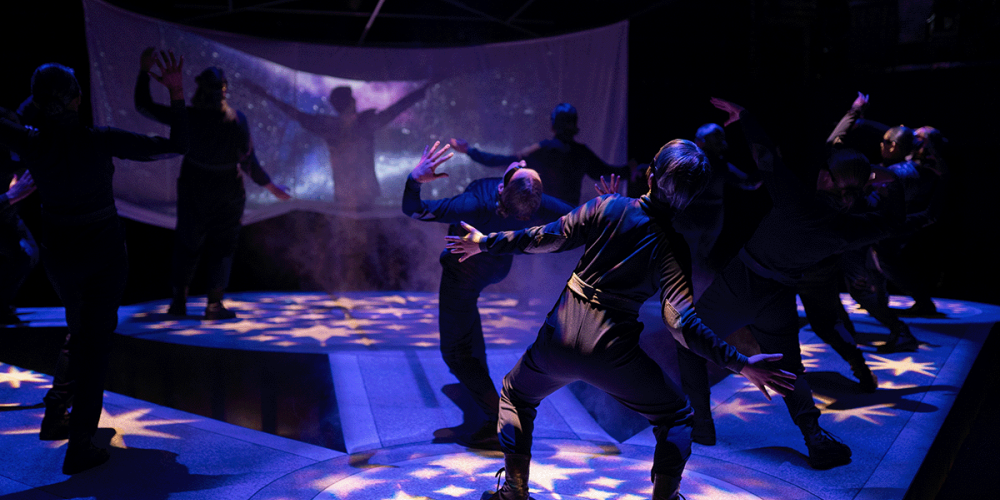 scene on stage of people stretching backwards from ULethbridge Drama Mainstage show "AI, Avatars & Aliens: A Speculative Cabaret".