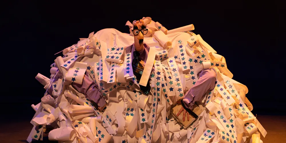 A foot with a face on it sticking out of a mound of paper strips with stars on it.