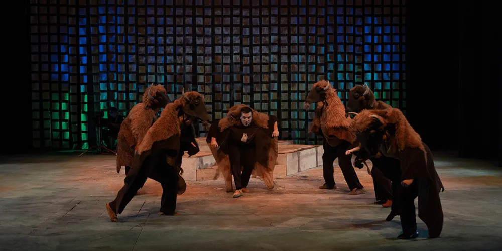 stage scene from ULethbridge Drama Mainstage production of Yisstsiiyi. Actors dressed as bison around another bison character.