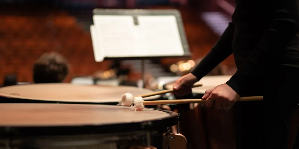 close up of a person playing on timpani with mallets