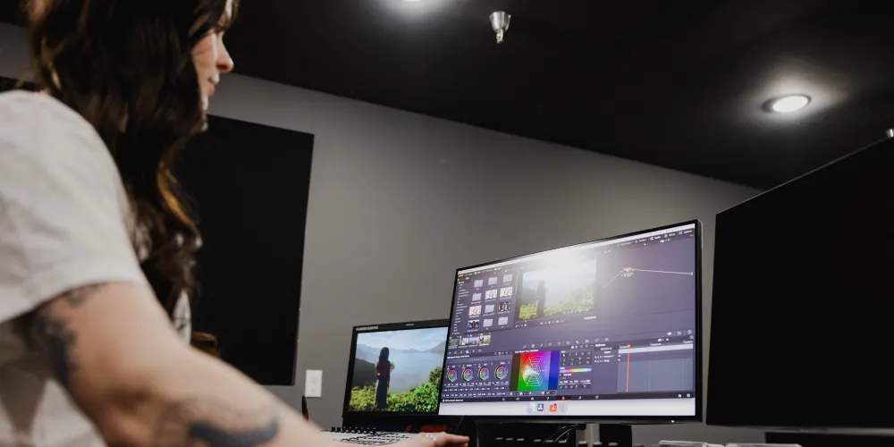 A woman sits at a computer editing a video file