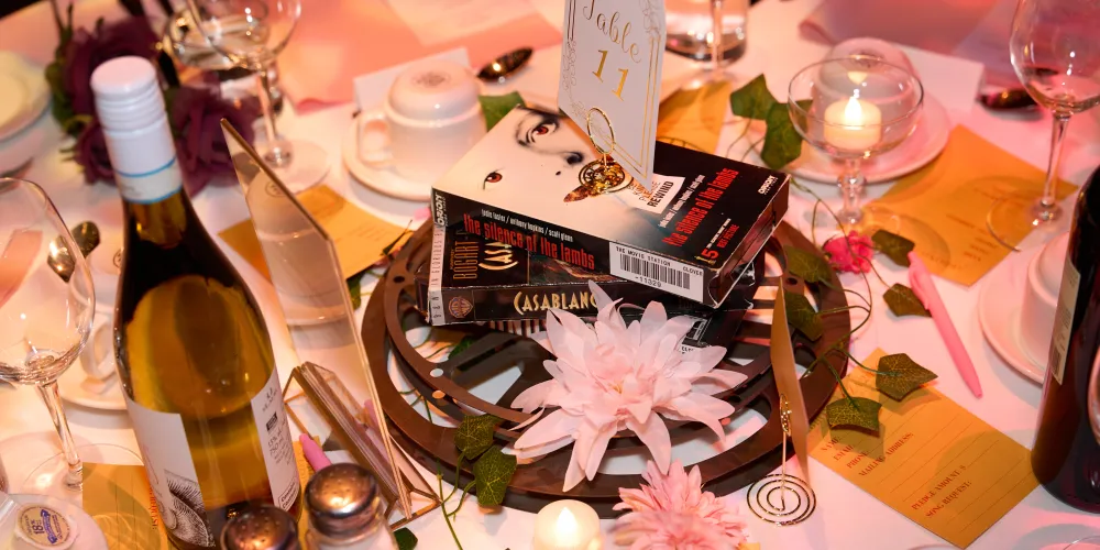 A table centrepiece with VCRs, a bottle of wine and flowers