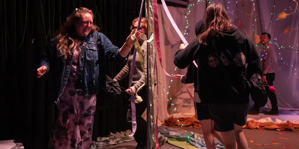A group of people dance around a maypole.