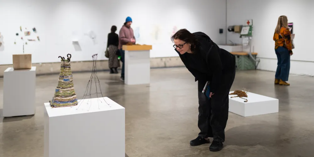 A person looks at a work of art on a plinth at an exhibit.