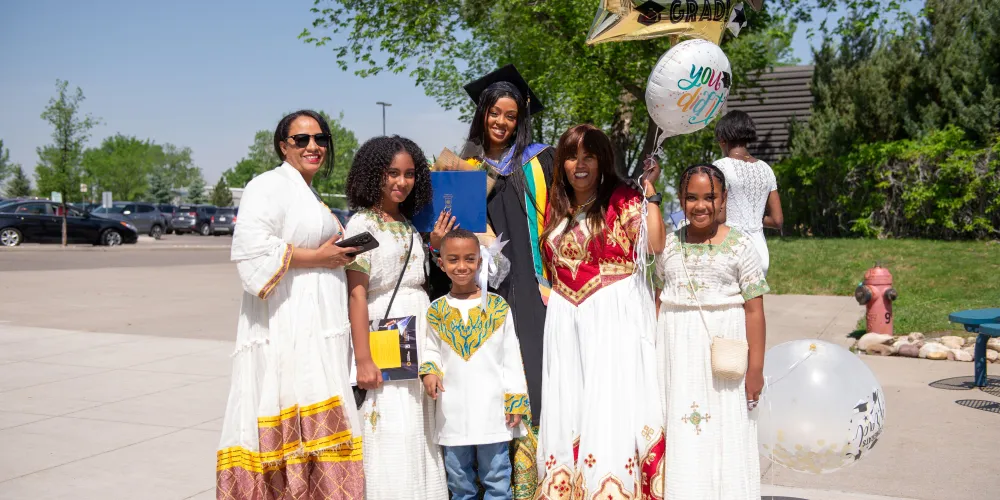 A family of six taking a group photo outside while holding balloons