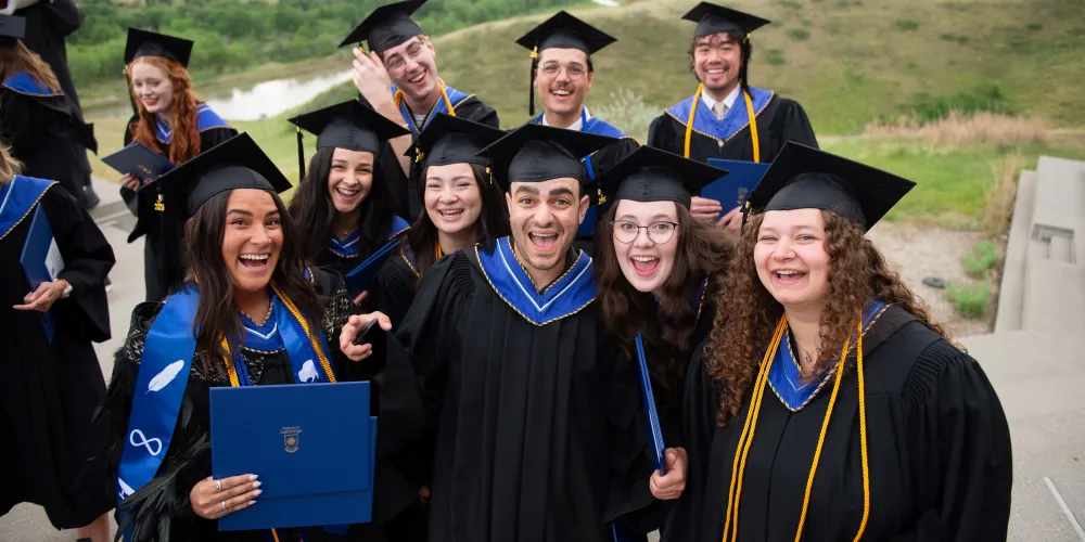 A large group photo of grads, all smiling, with the coulees in the background