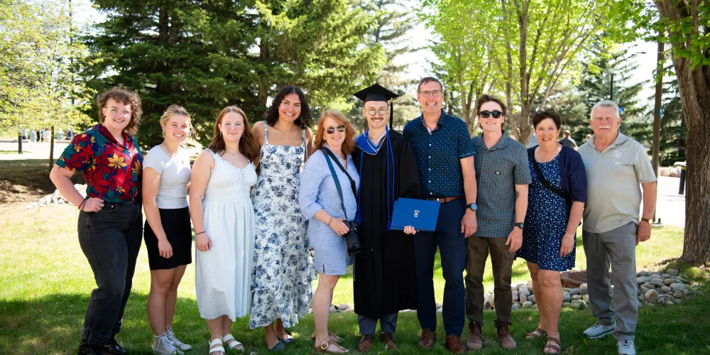 A large group photo of a grad in the middle and their guests on either side