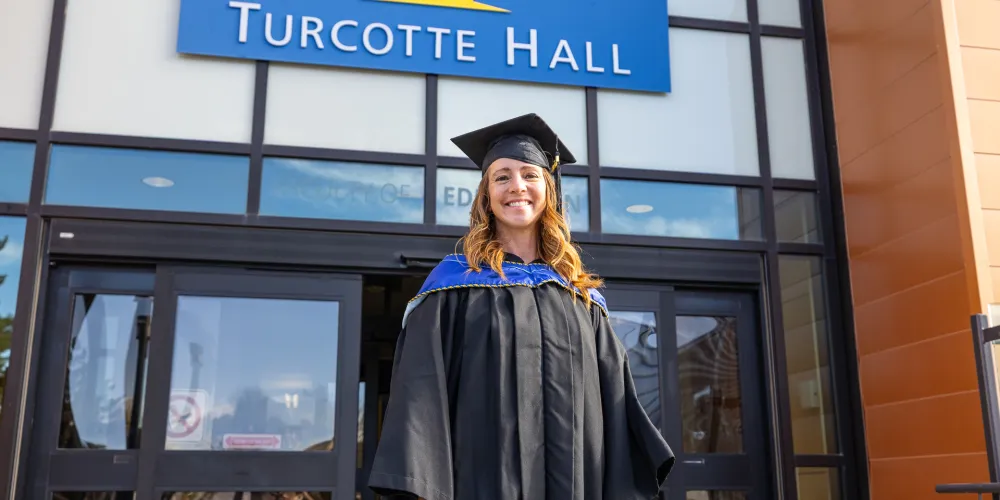 Fall 2026 convocation - student in front of Turcotte Hall