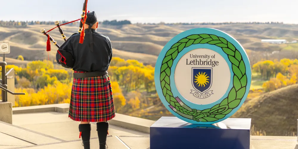 Fall 2026 convocation - bagpipe player facing the coulees