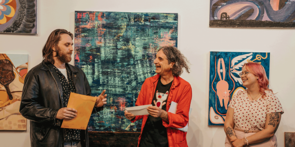 2023 Art Student Purchase Award recipients David Knight (left) talking, Jessica Colley (right) smiling, and Associate Professor David Miller (middle) laughing