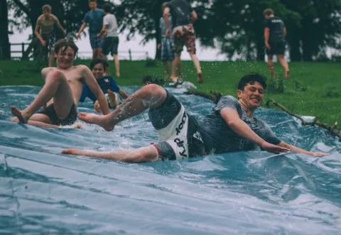 Youths sliding down a hill