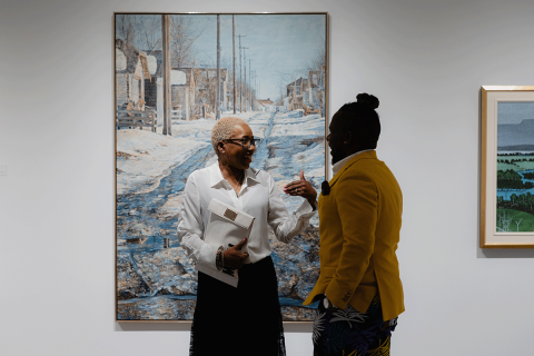Two people standing in front of a painting at Abbondanza fundraiser.