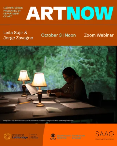 Photo of a reader sitting at a table with two lit table lamps, papers and books, with a forest projection in the background.